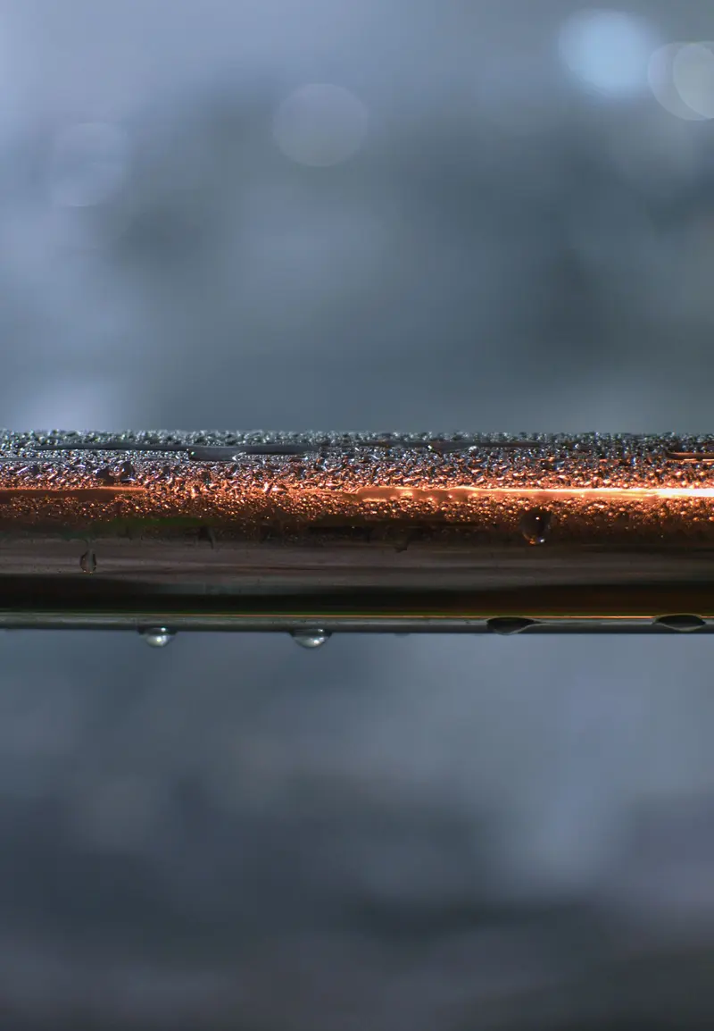 Detailed view of a metallic pipe covered with water droplets
