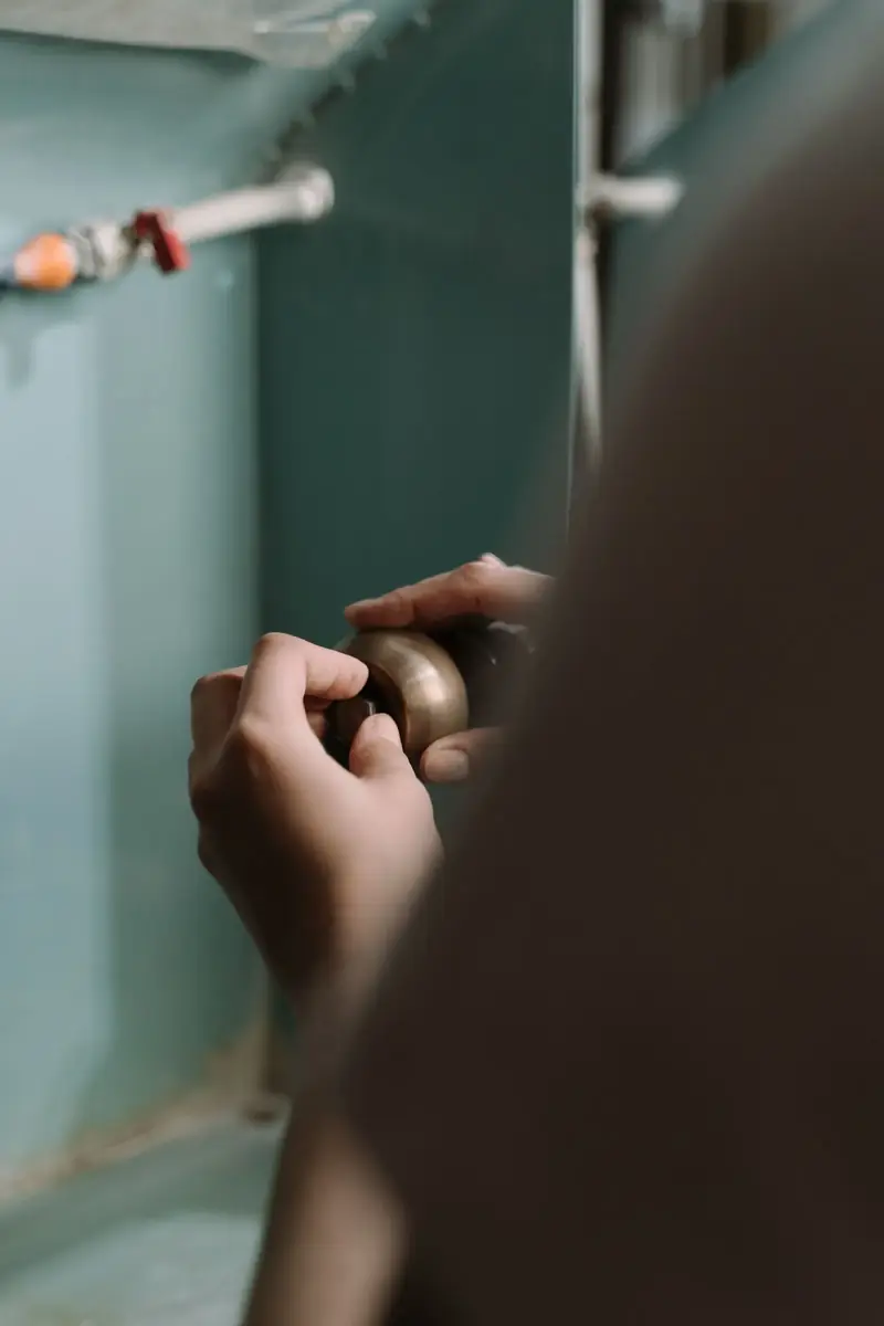 Plumber repairing a burst pipe under a kitchen sink